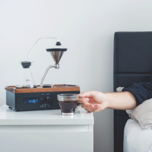 Barisieur Coffee Maker and Alarm Clock placed on a bedside table, brewing coffee next to a bed