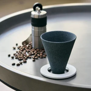 Cerapotta ceramic coffee filter with a ring holder, placed on a table with coffee beans and a manual grinder