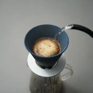 Cerapotta ceramic coffee filter brewing coffee as water is poured, placed on a glass carafe