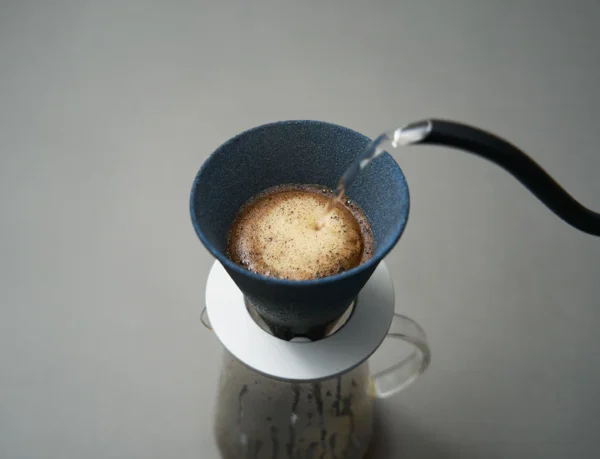 Cerapotta ceramic coffee filter brewing coffee as water is poured, placed on a glass carafe