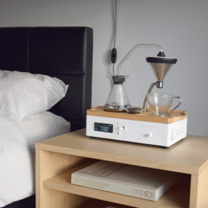 Barisieur Coffee Maker and Alarm Clock placed on a bedside table, brewing coffee next to a bed