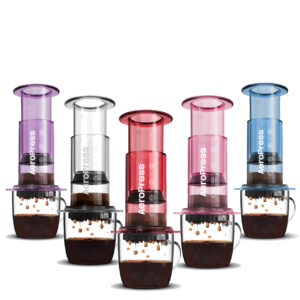 Five AeroPress coffee makers in vibrant colors (purple, clear, red, pink, and blue) brewing coffee into glass cups.