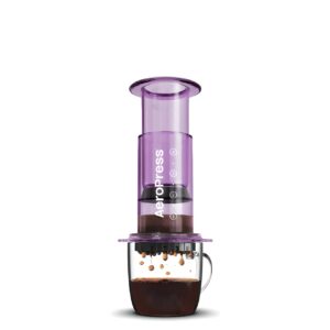 Purple AeroPress coffee maker with fresh coffee dripping into a glass.