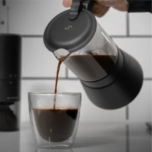 Pouring coffee from the ClearBrew black Moka pot by Joy Resolve into a glass cup