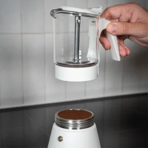 Person assembling the ClearBrew white Moka pot by Joy Resolve with coffee grounds in base