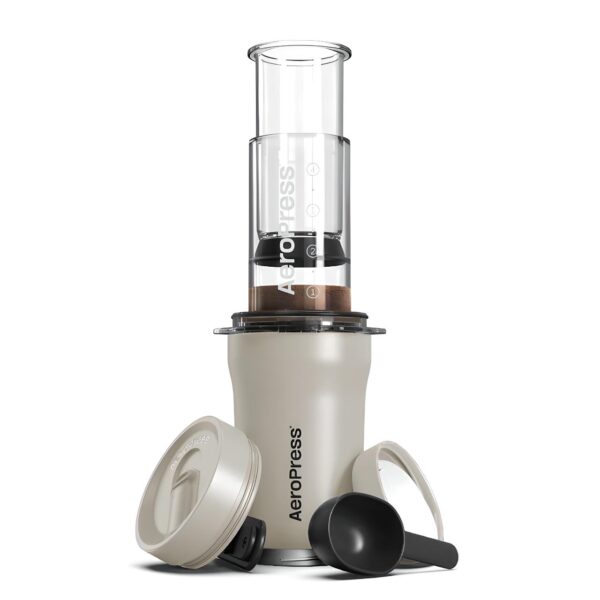 Cream Aeropress Go Plus Travel Coffee Maker with accessories, including lid, plunger, scoop, and filter holder.